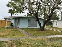 Light blue house with carport and a large tree in the front yard at 21179 Glendale Ave, Port Charlotte, FL 33952