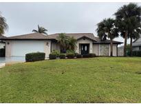 Single-story home with a landscaped lawn and attached garage at 294 Rotonda Cir, Rotonda West, FL 33947