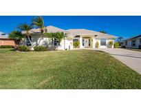 Well-maintained single-story home with lush lawn, palm trees, and neutral color palette at 40 Bunker Pl, Rotonda West, FL 33947