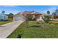 Single-story home with a large front yard, driveway, and attached garage at 411 Boundary Blvd, Rotonda West, FL 33947