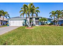 Charming home featuring a manicured lawn and complemented by swaying palm trees at 429 Rotonda Cir, Rotonda West, FL 33947