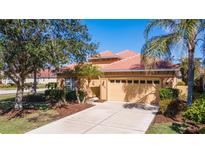 House exterior with a two-car garage and lush landscaping at 5560 Club View Ln, North Port, FL 34287