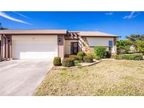 Front view of charming villa with attached garage, landscaping, and a well-maintained lawn at 615 Apple Ln, Englewood, FL 34223