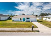 Cute ranch-style home with a white exterior, teal accents, and a well-manicured lawn at 7035 Sunnybrook Blvd, Englewood, FL 34224