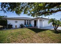 White single-story house with teal chairs on the patio, lush green lawn, and a driveway at 7336 Brookhaven Ter, Englewood, FL 34224