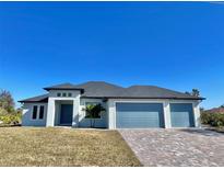 Single-story home with three-car garage and paver driveway at 7410 Grand Concourse St, Englewood, FL 34224