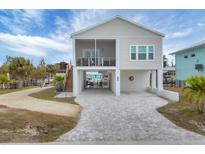 Two-story home with light beige siding, screened porch and paved driveway at 10451 Sherman St, Englewood, FL 34224