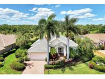 Aerial view of a single-Gathering home with a tile roof, palm trees, and lush landscaping at 13760 Long Lake Ln, Port Charlotte, FL 33953