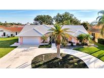 Beautiful single-story home with circular driveway, tropical landscaping, and an attached two-car garage at 1443 Quail Lake Dr, Venice, FL 34293