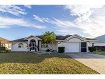 Single-story home with a two-car garage and landscaped lawn at 23111 Mineral Ave, Port Charlotte, FL 33954