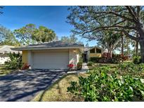 Charming single-story home featuring a two-car garage and a beautifully landscaped front yard with mature trees and flowering plants at 232 Southampton Ln # 259, Venice, FL 34293