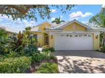 Bright yellow house with white garage and well-manicured landscaping at 523 Fallbrook Dr, Venice, FL 34292