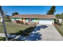 Charming single-story home featuring a well-manicured lawn, light green paint, and a spacious two-car garage at 6543 Coliseum Blvd, Port Charlotte, FL 33981