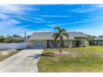 Cute Florida home with a palm tree, white fence, and spacious driveway at 7586 Sea Mist Dr, Port Charlotte, FL 33981