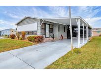 Gray mobile home with carport, landscaping, and paved driveway at 844 Seabrooke Ct, Englewood, FL 34223