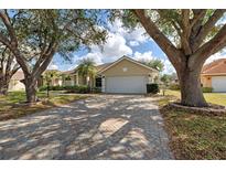 Beautiful single-story home featuring a brick paved driveway and mature trees on a sunny day at 1216 Whitney Dr, Venice, FL 34293
