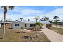 Charming single-story home featuring a metal roof, a covered carport, and a well-maintained front yard with mature palm trees at 1455 New Point Comfort Rd, Englewood, FL 34223