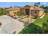 Tan house with a brown roof, landscaped yard, and a long driveway at 15204 Aquarius Cir, Port Charlotte, FL 33981