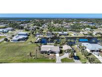 Aerial view of canal-front home with private dock, lush landscaping, and neighborhood views at 18198 Burkholder Cir, Port Charlotte, FL 33948