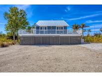 Charming elevated beach house with a metal roof and a deck overlooking the landscape at 331 Bocilla Dr, Placida, FL 33946