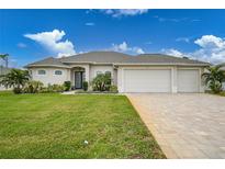 Single-story home with three-car garage, landscaped lawn, and paver driveway at 5 Broadmoor Ln, Rotonda West, FL 33947