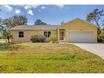 Charming yellow single-story home with attached two-car garage and well-maintained lawn at 6125 Higgins Ln, Englewood, FL 34224