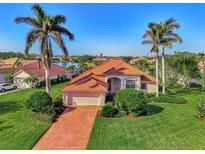 Beautiful single-Gathering home with a red tile roof, paver driveway, lush lawn, and tropical palm trees at 14405 Silver Lakes Cir, Port Charlotte, FL 33953