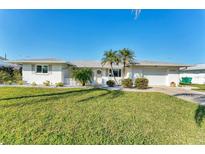 Charming single-story home with a well-manicured lawn, palm trees, and a bright white exterior at 1710 Loralin Dr, Englewood, FL 34223