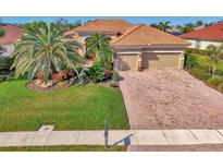 Stunning single-Gathering home featuring lush landscaping, a brick driveway, and a tile roof at 2660 Sable Palm Way, Port Charlotte, FL 33953