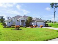 Charming single-story home featuring a manicured lawn, lush landscaping, and a welcoming entrance at 39 Medalist Cir, Rotonda West, FL 33947