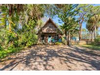 Charming A-frame home with a second-story balcony surrounded by lush, tropical foliage at 681 Olive St, Englewood, FL 34223