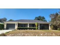 Single-story house with a gray roof, attached garage, and well-maintained landscaping at 6981 Tuxedo St, Englewood, FL 34224