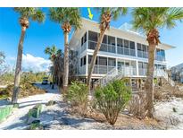 Island home on stilts with three stories and a large screened porch surrounded by Palm Trees at 7482 Palm Island Dr # 2522, Placida, FL 33946