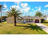 Charming single-story home with well-manicured lawn and mature palm trees at 84 Caddy Rd, Rotonda West, FL 33947