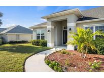 Beautifully landscaped front yard with walkway leading to the covered entryway and dark front door at 23 Fairway Rd, Rotonda West, FL 33947