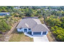 Stunning aerial view of a home featuring lush landscaping, a modern design, and a spacious three-car garage at 7282 Printer St, Port Charlotte, FL 33981