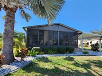 View of the screened sunroom with manicured landscaping and a palm tree in the front yard at 810 Manchester Ct, Englewood, FL 34223