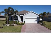 Single-story home with gray exterior, white garage door, and palm trees at 24692 Rio Villa Lakes Cir, Punta Gorda, FL 33950