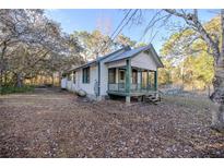 White house with green trim and porch, nestled on a wooded lot at 11317 Salina St, Brooksville, FL 34614