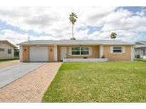 Single-story house with a peach-colored exterior, a neatly landscaped lawn, and a brick driveway at 4020 Headsail Dr, New Port Richey, FL 34652