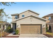 Two-story house with beige exterior, two-car garage, and landscaping at 10710 Southern Forest Dr, Riverview, FL 33578