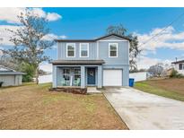 Newly built two-story home with gray siding, a porch, and a driveway at 27096 Wakefield Dr, Brooksville, FL 34602