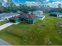 Aerial view of a teal house with brown roof, detached garage, and fenced backyard at 4154 Duluth Ter, North Port, FL 34286