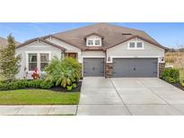 Two-story house with gray siding, stone accents, and a three-car garage at 11701 Brighton Knoll Loop, Riverview, FL 33579