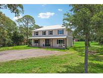 Two-story house with a metal roof, large yard, and driveway at 3011 39Th E St, Bradenton, FL 34208