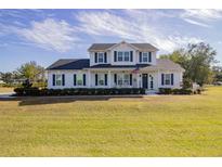 Two-story white house with dark shutters, front porch, and landscaped yard at 14818 Grady Sweat Ln, Wimauma, FL 33598