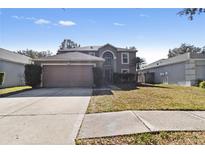 Two-story home featuring an attached garage, neutral paint, mature landscaping, and a well-manicured lawn at 19245 Wood Sage Dr, Tampa, FL 33647