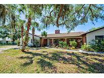 Charming brick home with mature landscaping and a welcoming front entrance shaded by mature trees at 1061 Owl Dr, Englewood, FL 34223