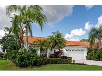 Single-story home with tile roof, lush landscaping, and a two-car garage at 4815 Tamarack Trl, Venice, FL 34293