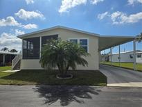 Charming home with a screened-in porch, carport, and a well-maintained front lawn on a sunny day at 428 Boxwood Dr, Venice, FL 34285